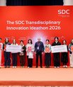 Group photo from the award ceremony at the SDC Transdisciplinary Innovation Ideathon 2026 in Beijing, showing the two winning teams and co-organiser Morten Foss on stage in front of a red backdrop. Several students hold diplomas and large cheques.