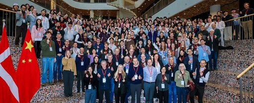 Large group photo from SDC Ideathon 2026 in Beijing, showing students, organisers, mentors and partners gathered on indoor steps between Danish and Chinese flags.
